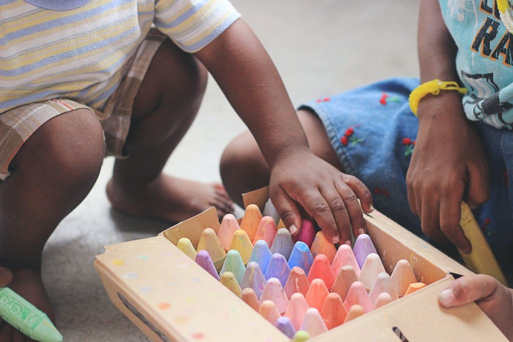 Two small children playing with a wooden toy