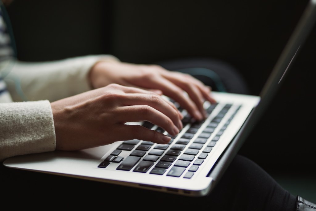 A stock photograph of someone writing on a laptop
