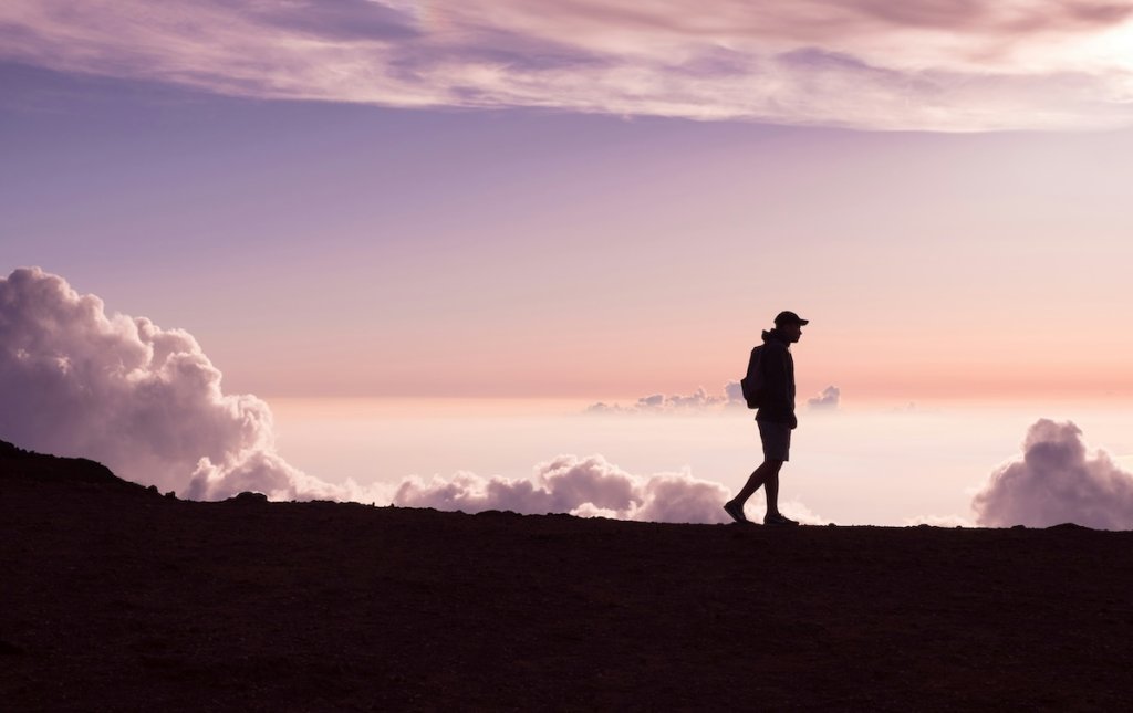 The silhouette of someone walking above the cloudline.